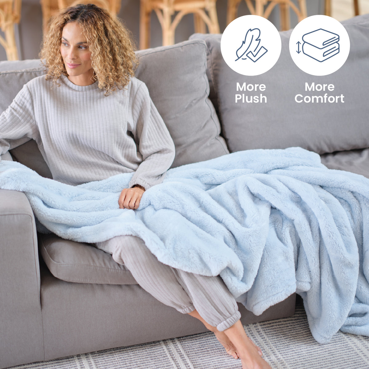 Infographic of our Premium Extra-Fluffy fabric with more plush and more comfort with a woman sitting on a grey sofa with a blue throw.