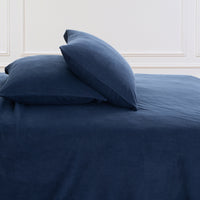 All-Season Microfleece Sheet Set pillowcases in Navy on a made bed against a white paneled wall