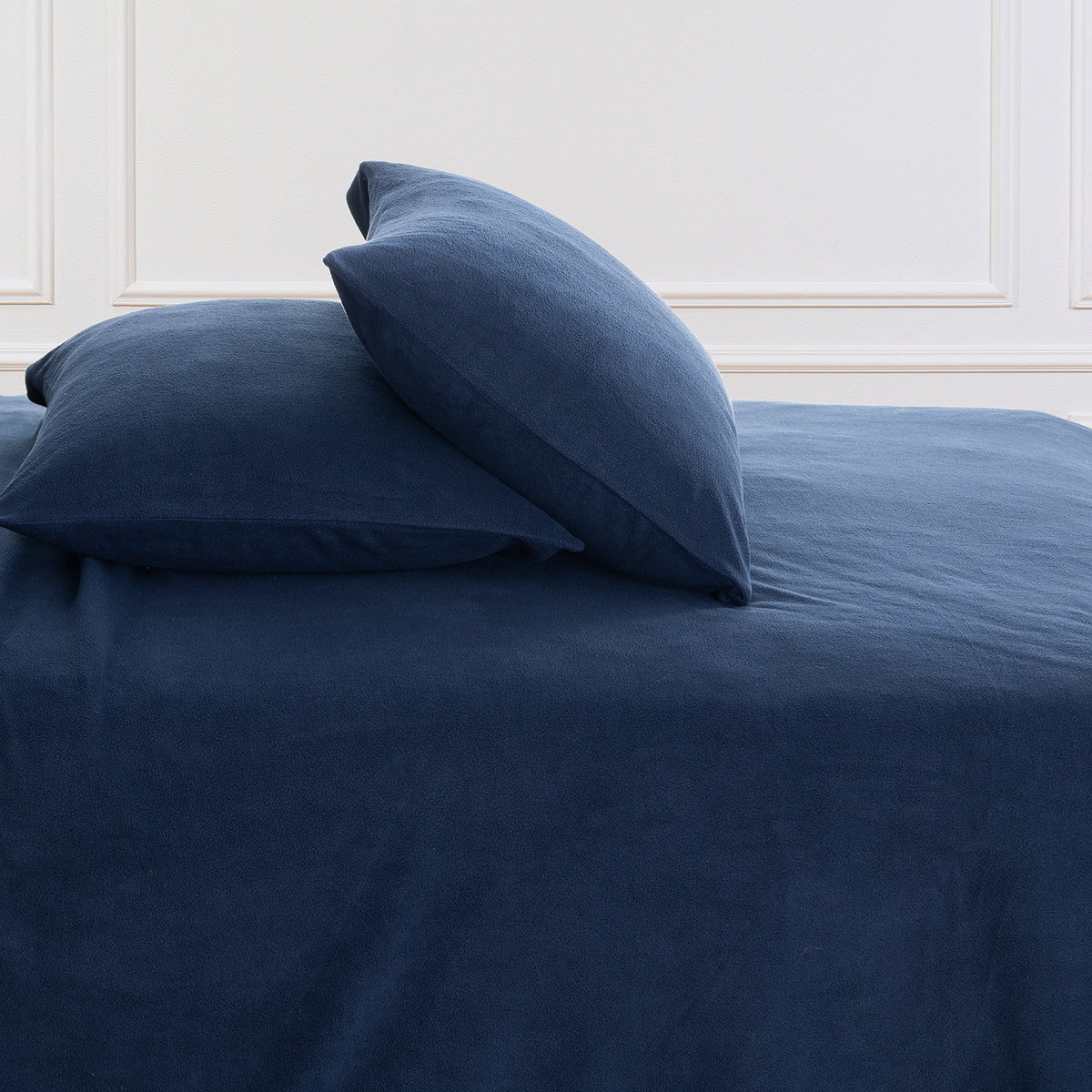 All-Season Microfleece Sheet Set pillowcases in Navy on a made bed against a white paneled wall