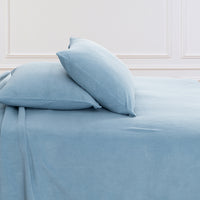 All-Season Microfleece Sheet Set pillowcases in Slate Blue on a made bed against a white paneled wall