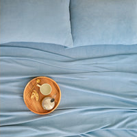 A wooden tray with a teacup resting on the All-Season Microfleece Sheet Set in Slate Blue, top view