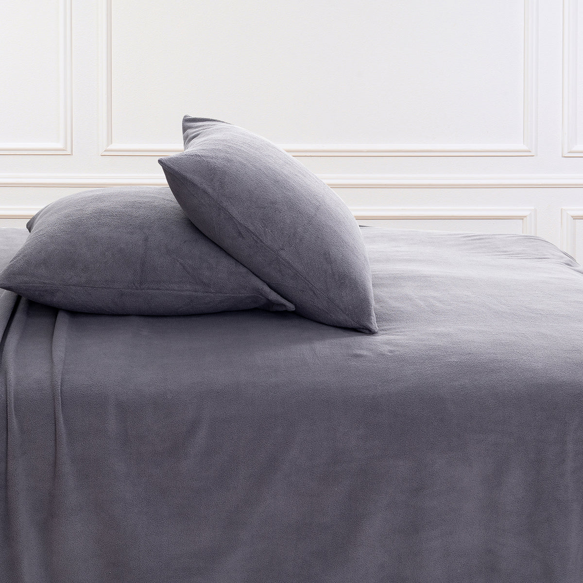 All-Season Microfleece Sheet Set pillowcases in Space Grey on a made bed against a white paneled wall