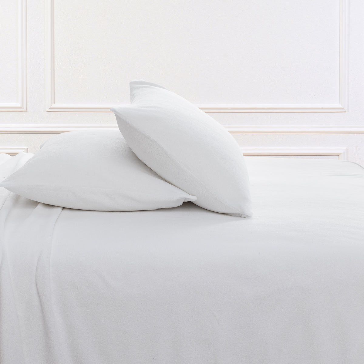 All-Season Microfleece Sheet Set pillowcases in True White on a made bed against a white paneled wall