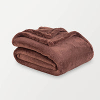 Folded brown blanket on a light gray background