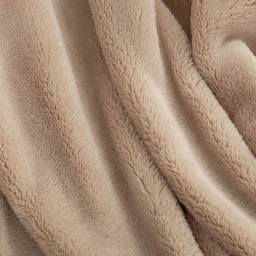 A close-up of a soft, plush fleece blanket in a warm beige color, draped in gentle folds to show its texture.