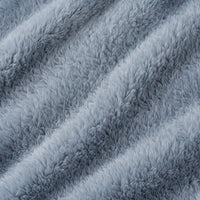 A close-up of a plush, shaggy faux fur or microfiber fabric in a dusty light blue-gray color, showing the soft texture and diagonal folds.