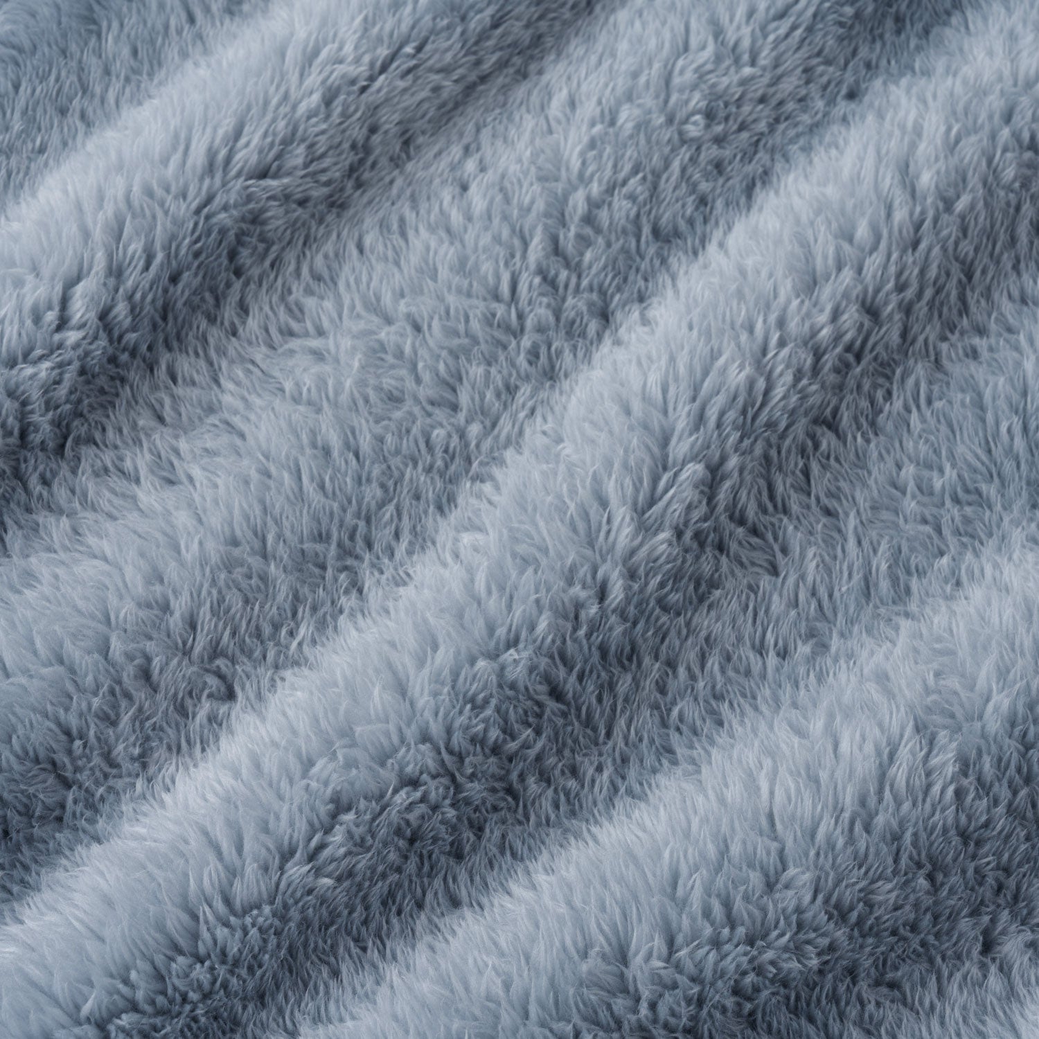 A close-up of a plush, shaggy faux fur or microfiber fabric in a dusty light blue-gray color, showing the soft texture and diagonal folds.