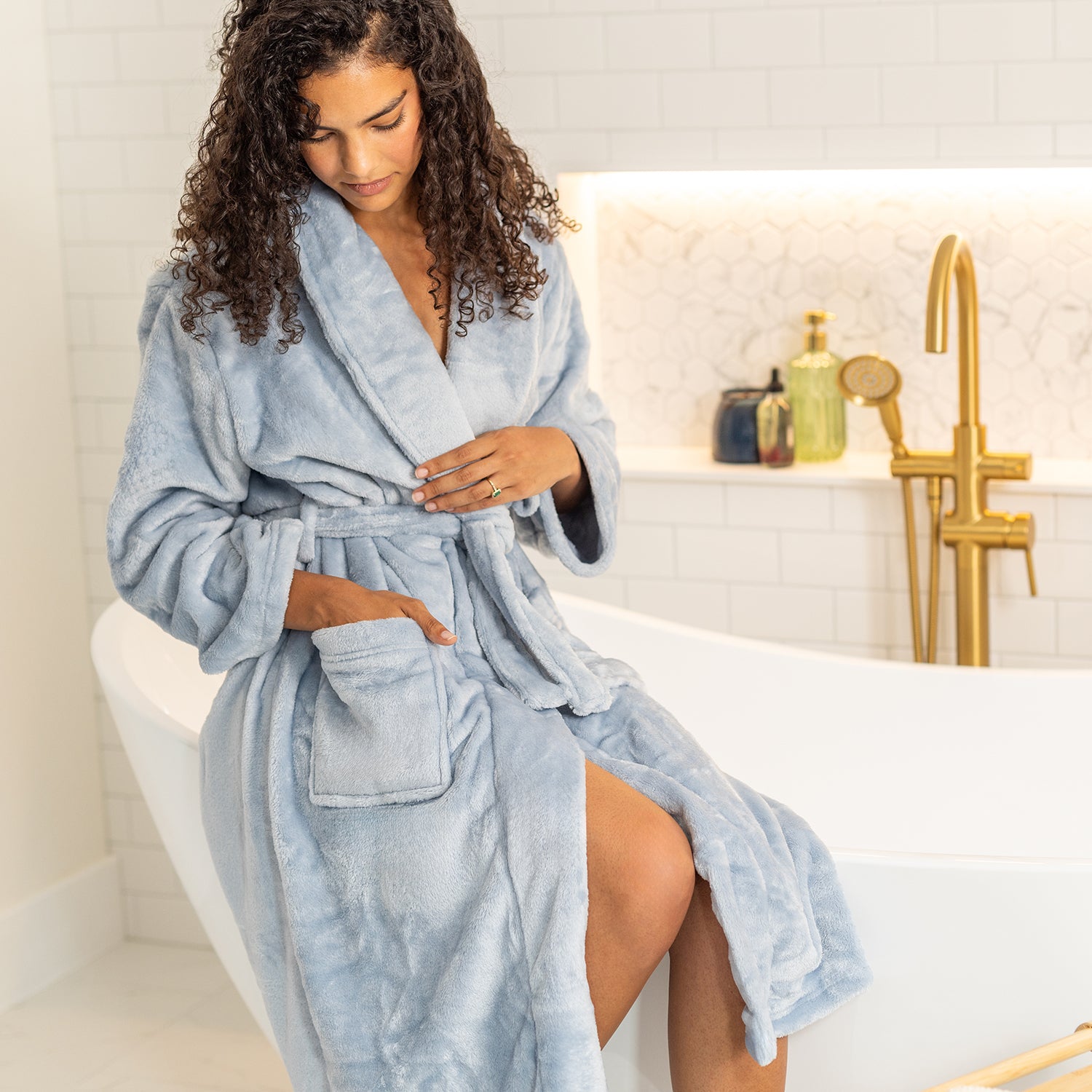 Woman wearing a light blue robe in a bathroom setting.