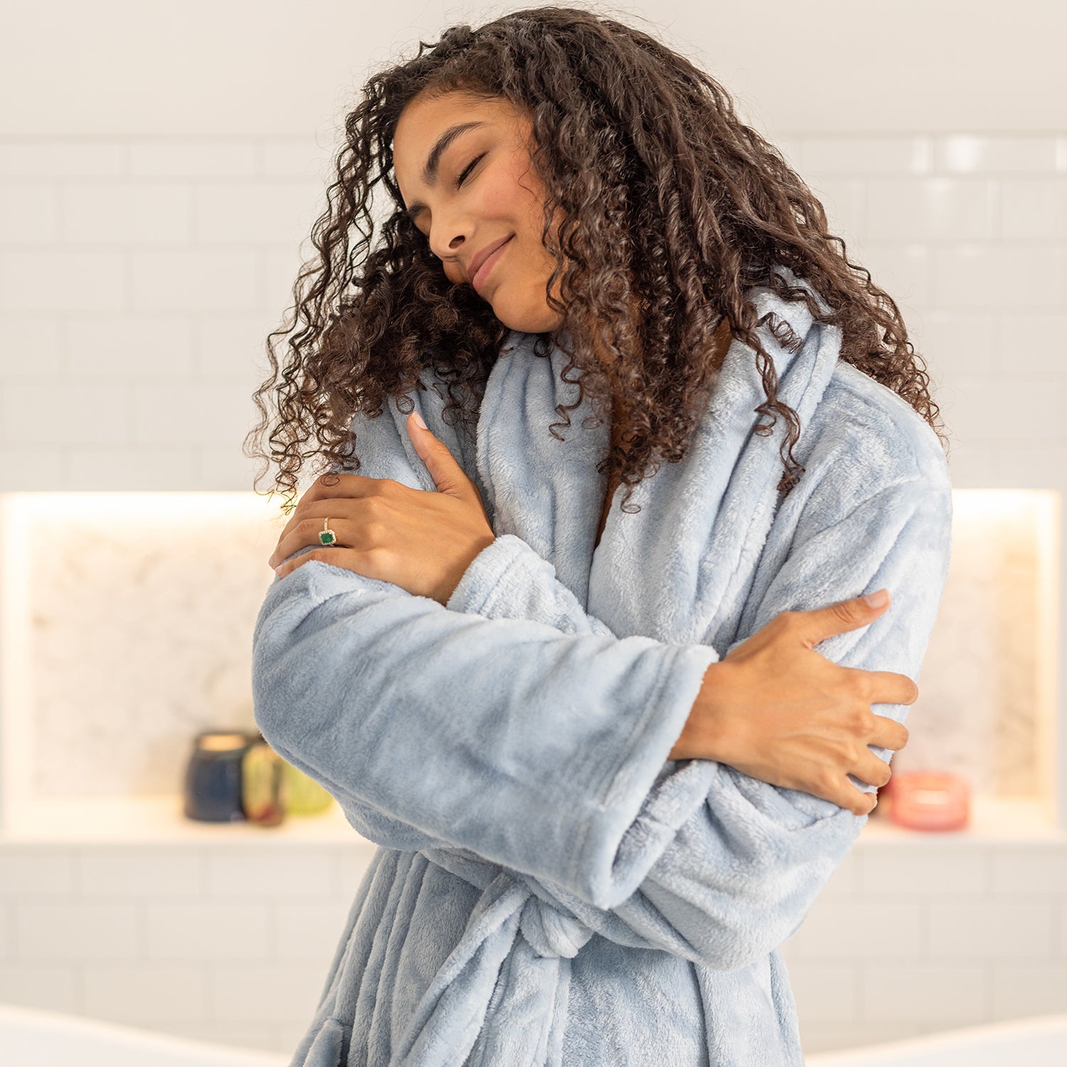 Woman wearing a light blue robe in a bathroom setting
