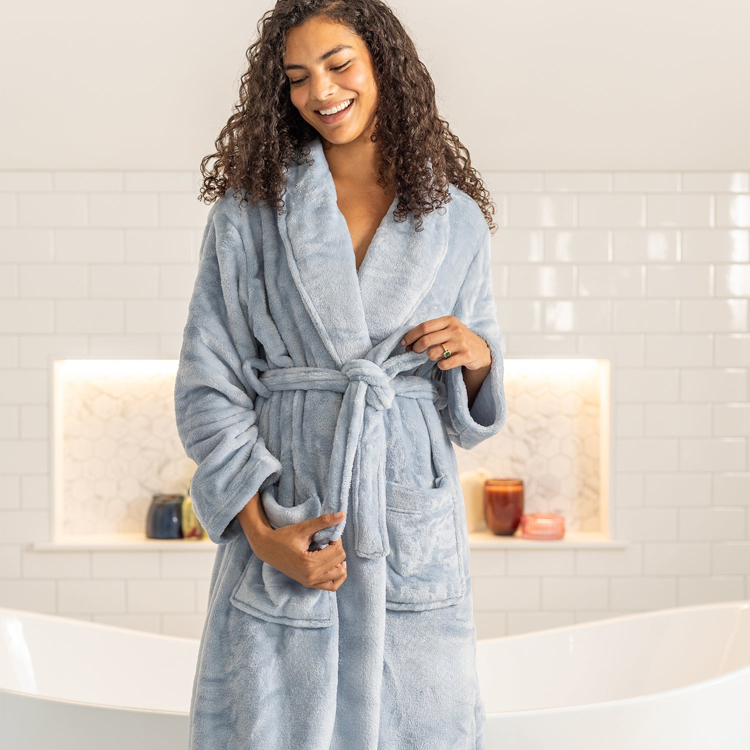 Woman wearing a light blue robe in a bathroom setting