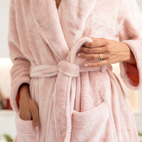 Person wearing a pink robe with a blurred background