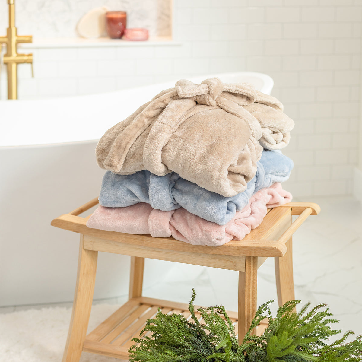Stack of folded robes on a wooden stool with a neutral background