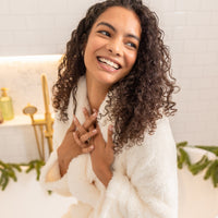Woman wrapped in a white robe with a blurred indoor background