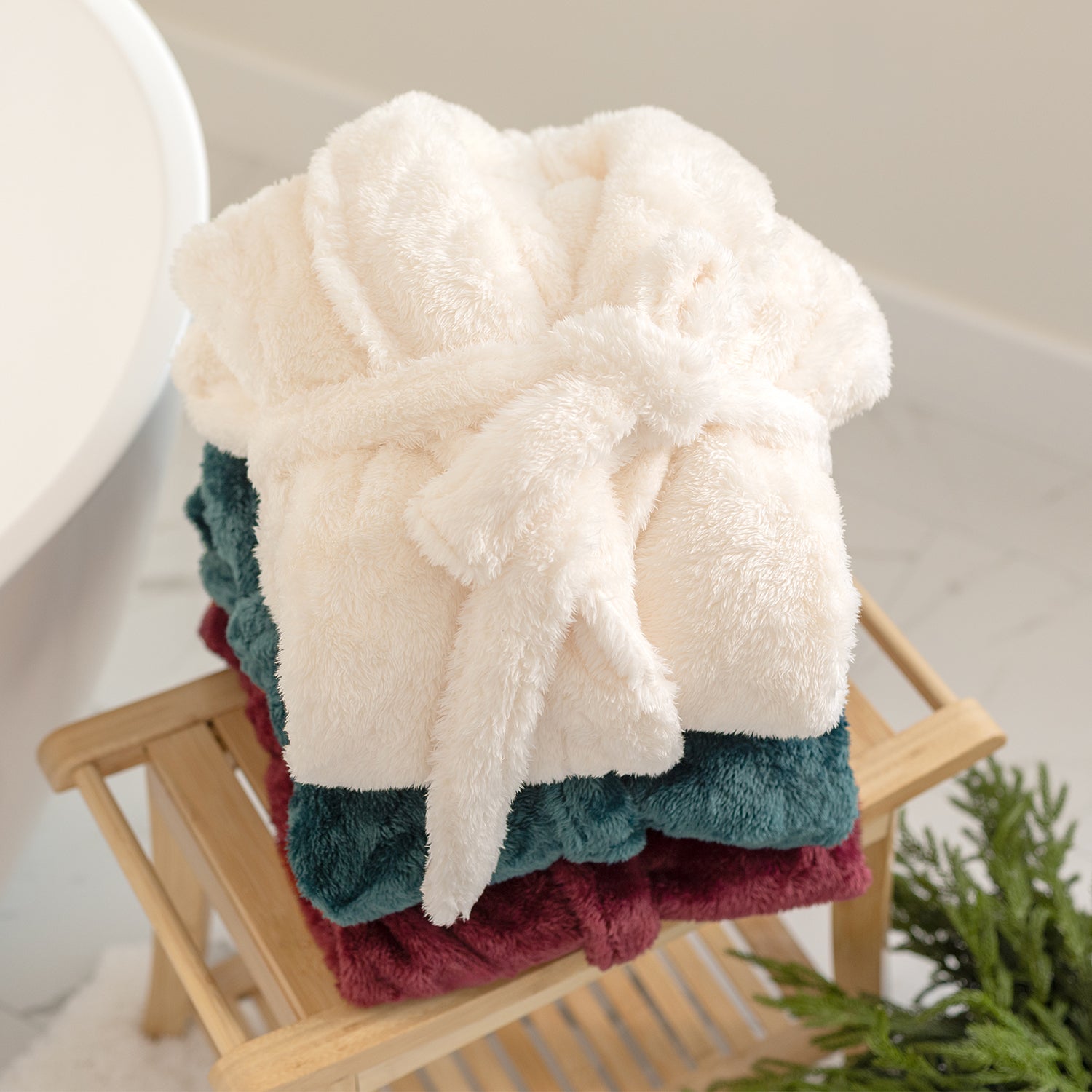 Stack of colorful robes on a wooden stool with a neutral background