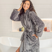 Woman wearing a gray plush robe in a bathroom setting
