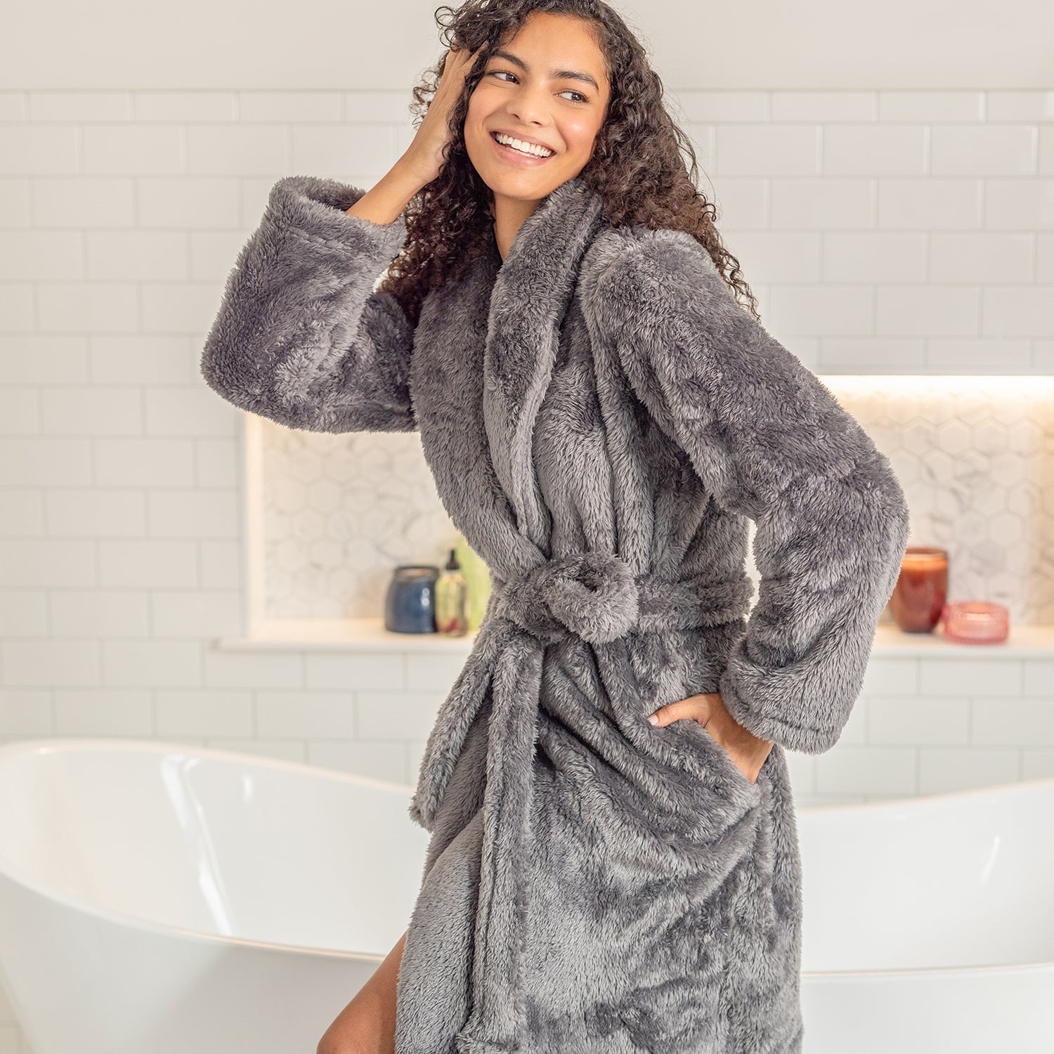 Woman wearing a gray plush robe in a bathroom setting