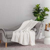 Gray sofa with a white blanket draped over it in a living room setting.
