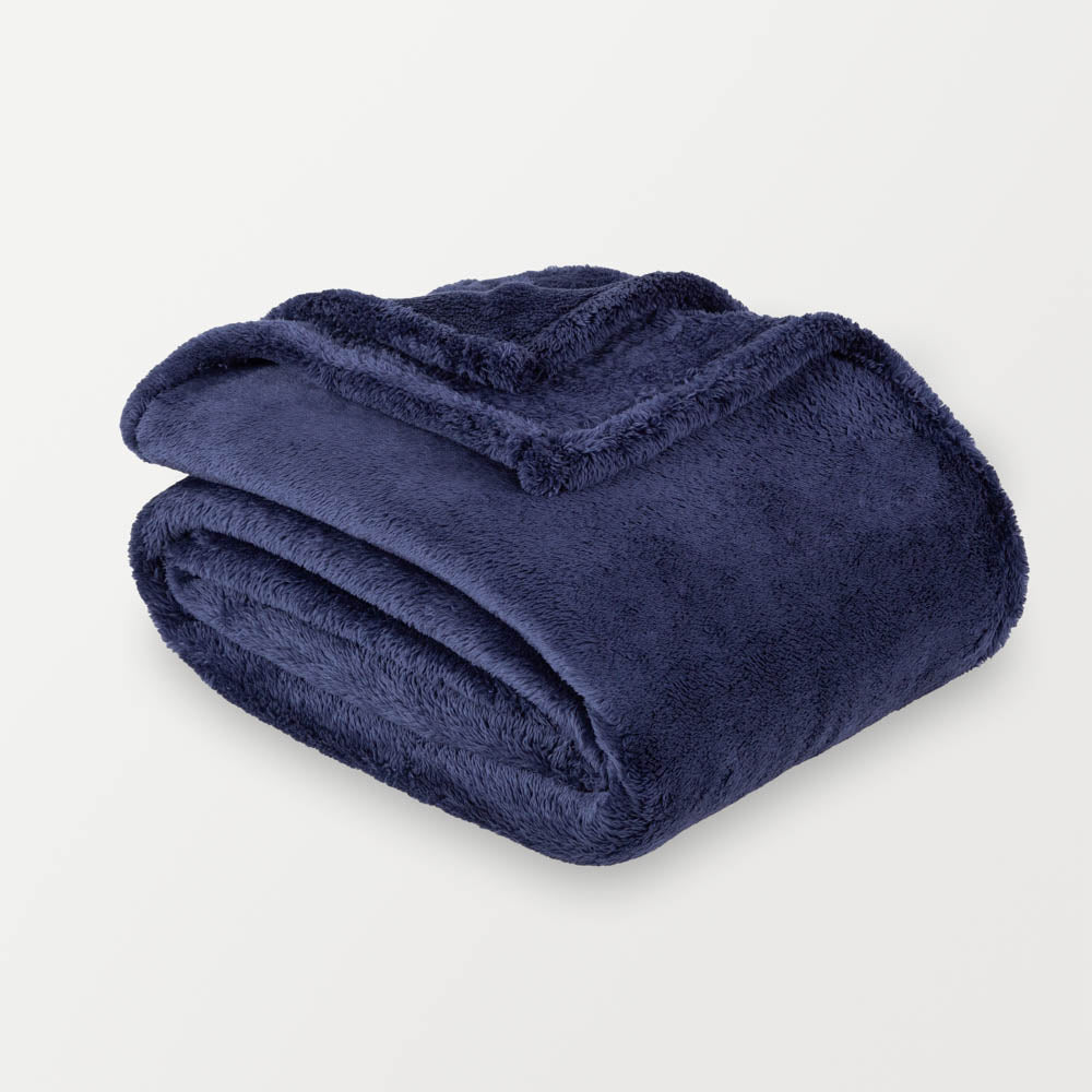 A blue fluffy blanket folded neatly on a white surface.