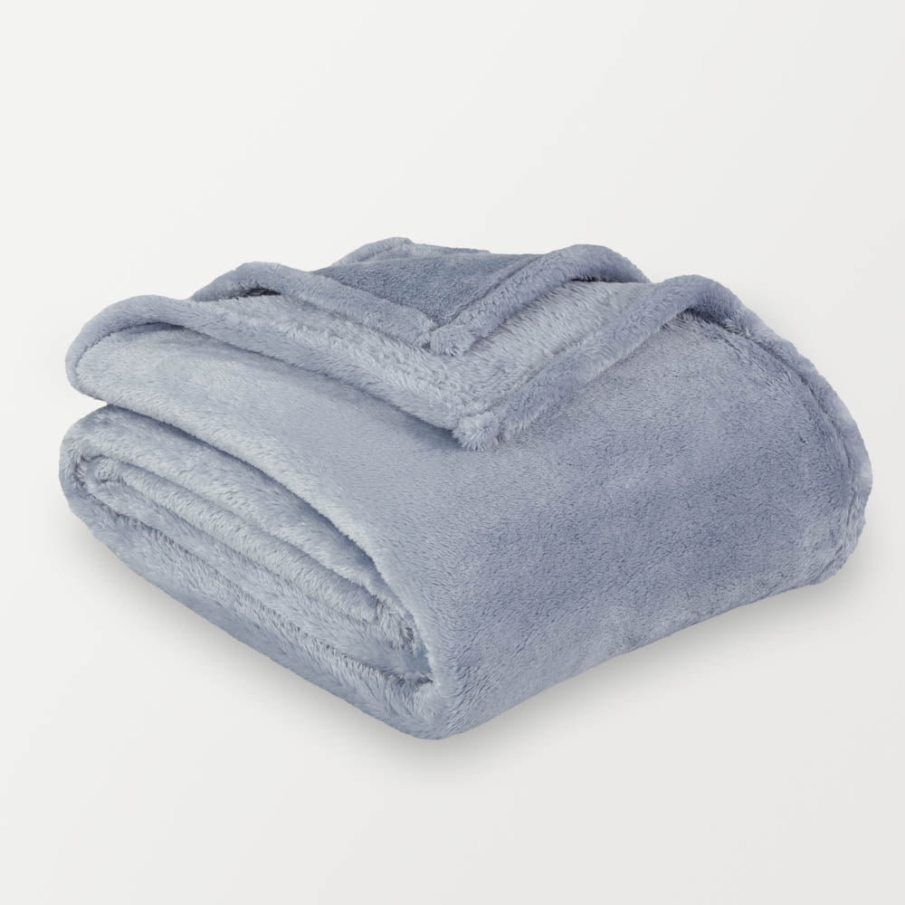 A blue fluffy blanket folded neatly on a white surface.
