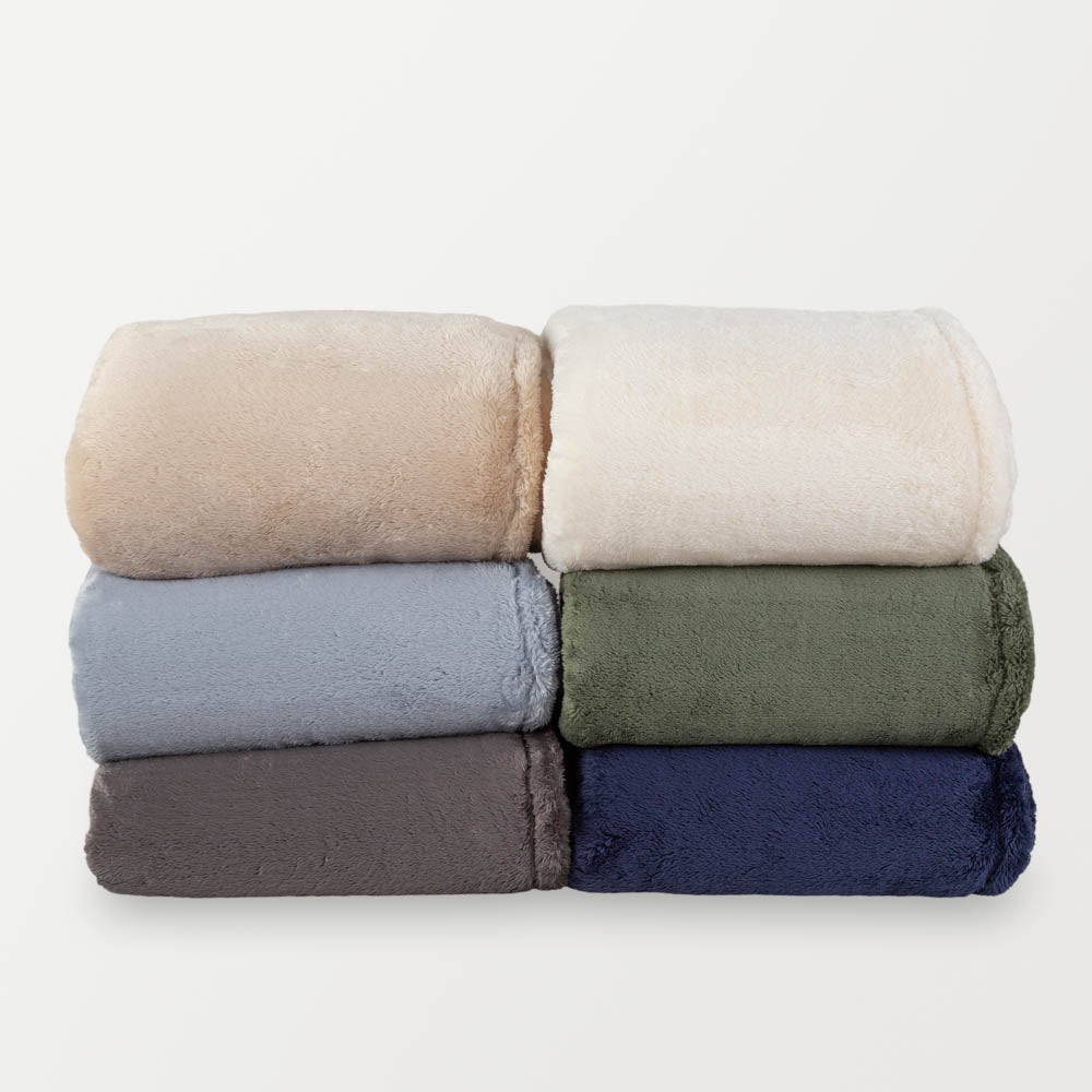 A stack of colorful fluffy blankets on a white background.
