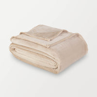 Beige velvety plush family blanket folded neatly on a white surface.
