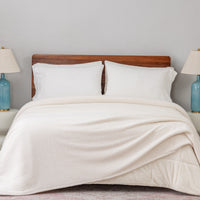 Bed with white bedding and wooden headboard in a room with two lamps.