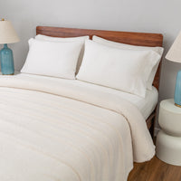 Neatly made bed with white bedding and pillows in a bedroom setting.