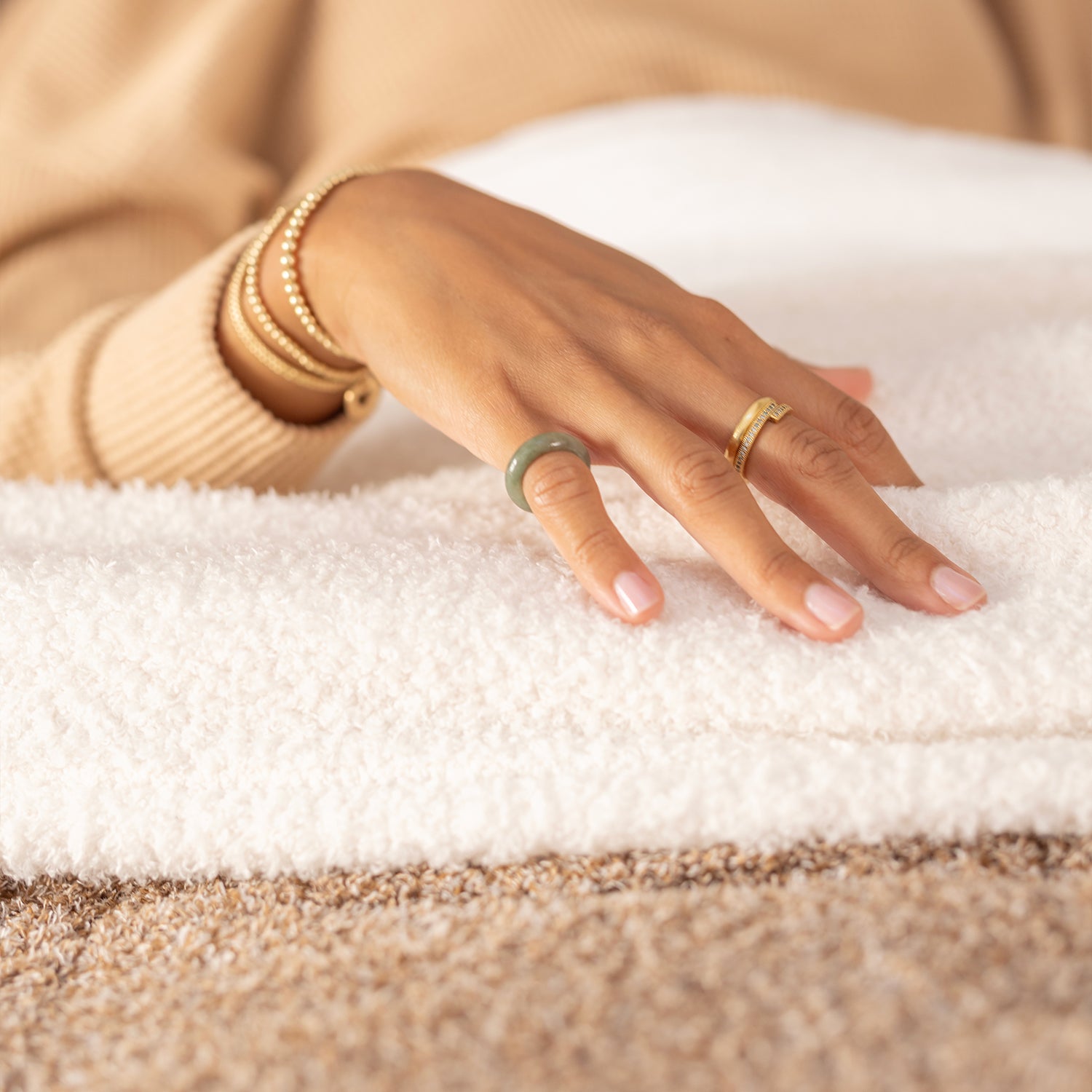 Hand with gold rings on a textured surface
