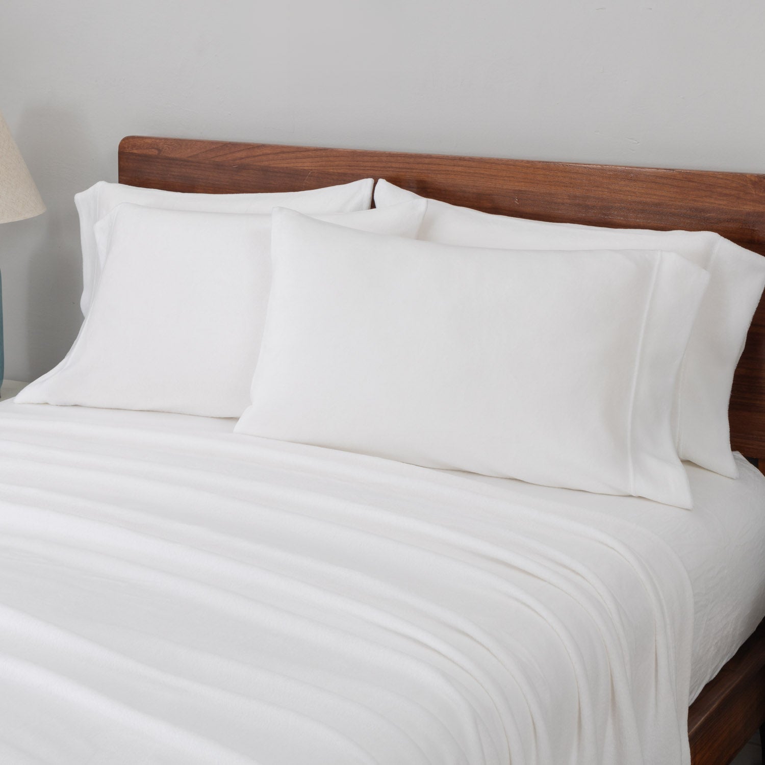 White bedding set on a bed with a wooden headboard.