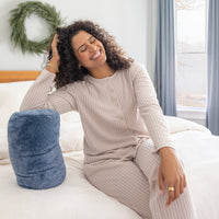 Woman sitting on a bed with a blue pillow, wearing a beige ribbed loungewear set.