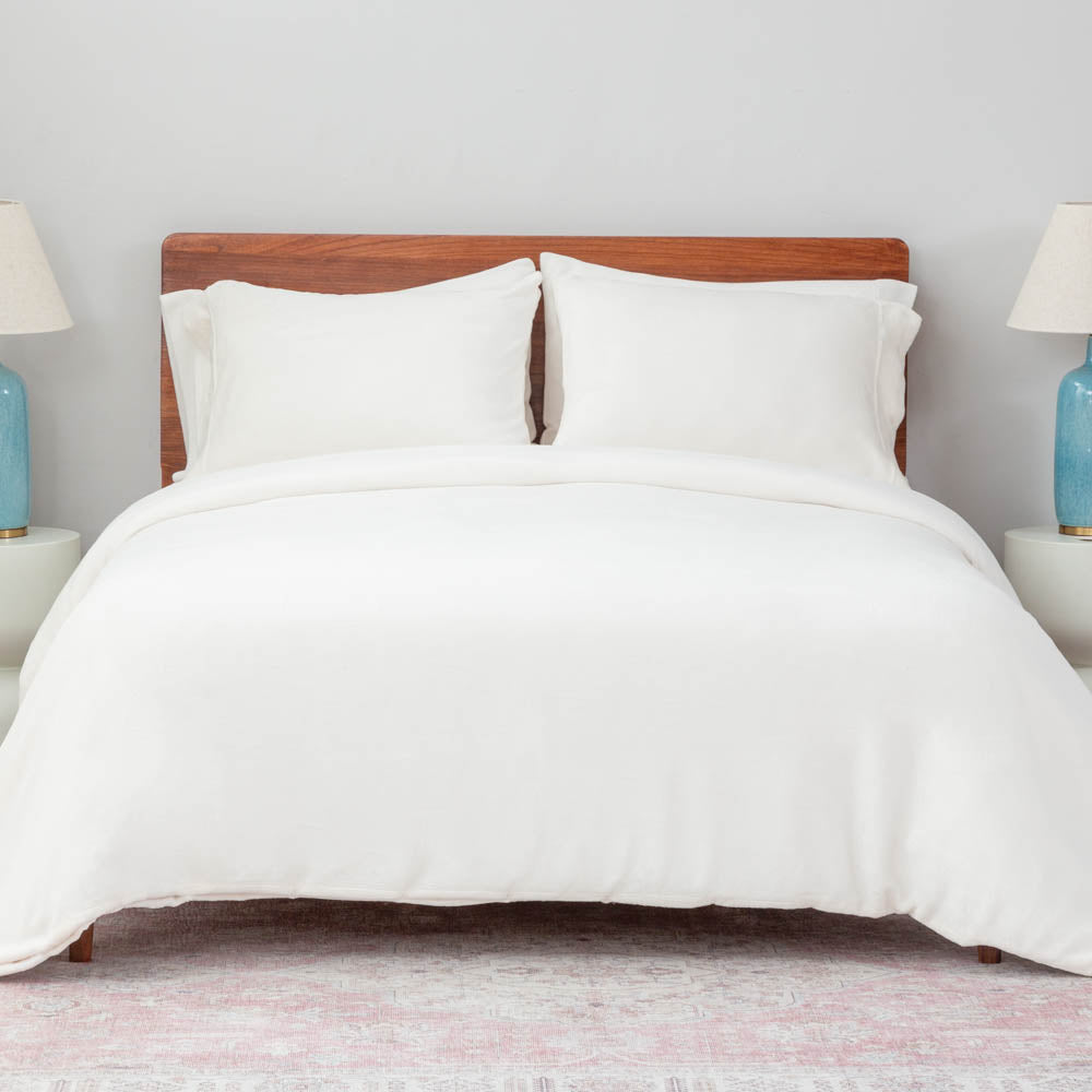 A bed made with the Cream VelvetLoft® Plush Duvet Cover Set and shams, creating a cozy and inviting look. 