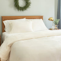Neatly made bed with white bedding in a bedroom setting.