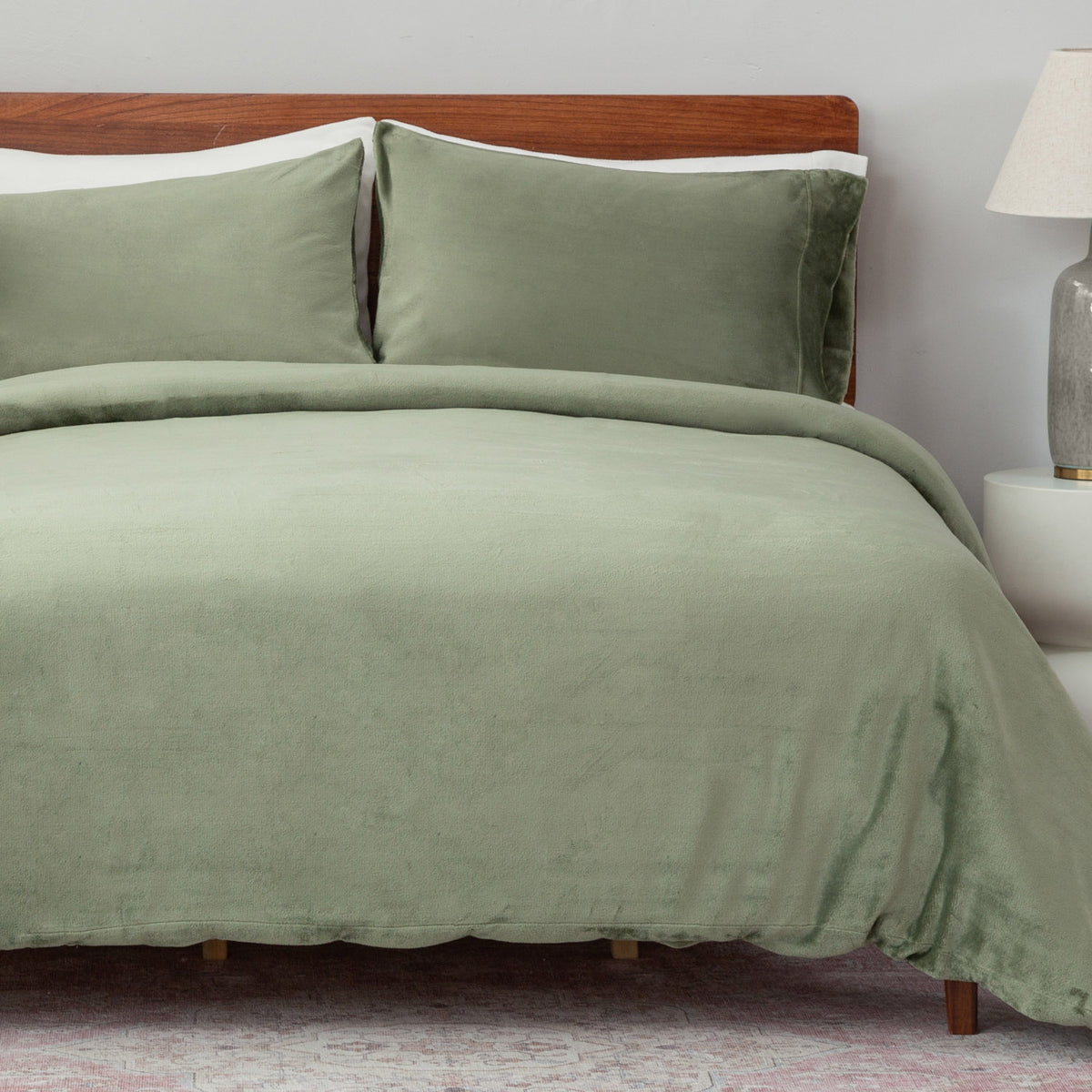 VelvetLoft® Duvet Set in Dark Sage on a made bed with a wooden headboard, angled view