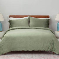 A bed made with the Dark sage green VelvetLoft® Plush Duvet Cover Set and shams, creating a cozy and inviting look. 