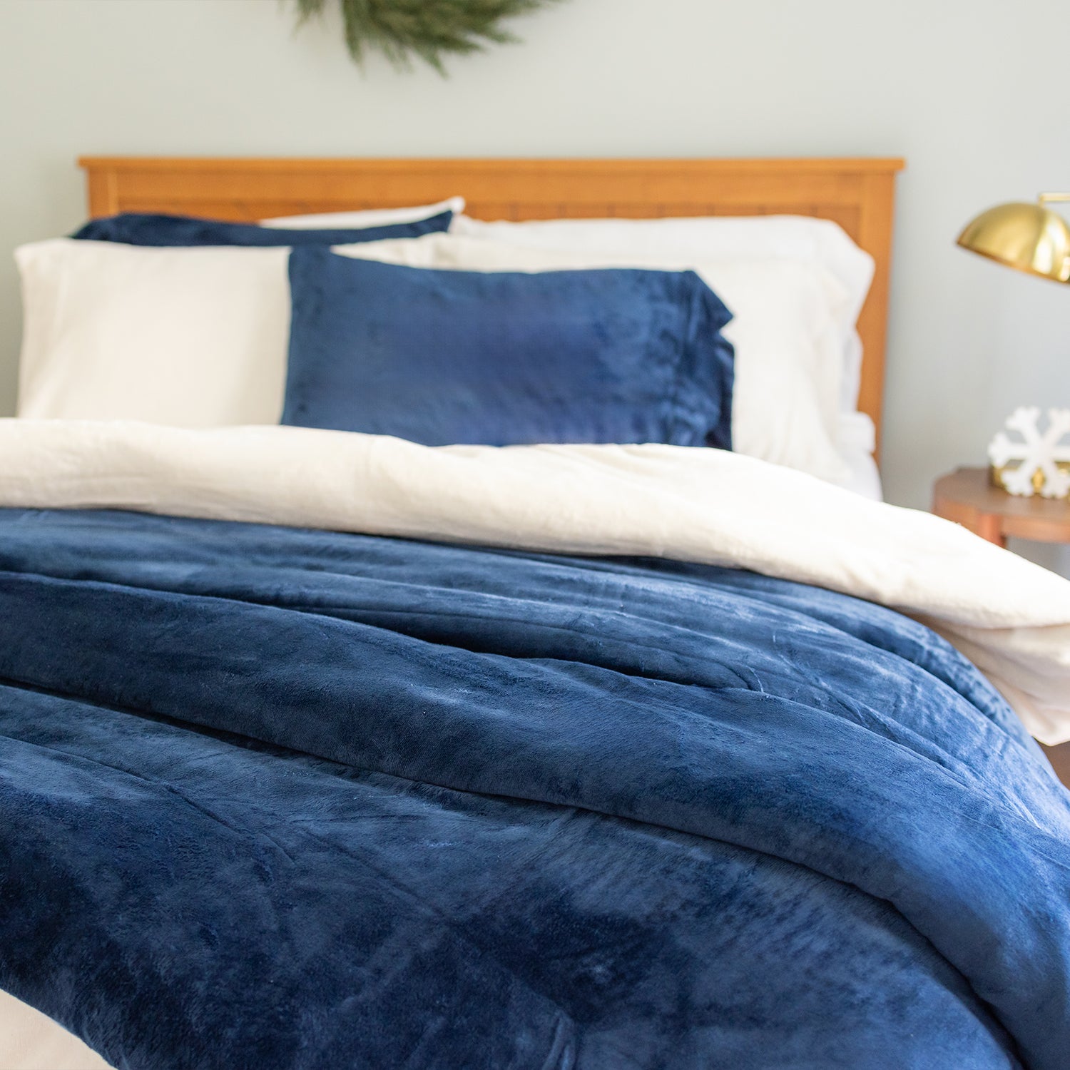Blue comforter and pillows on a bed with a wooden headboard.