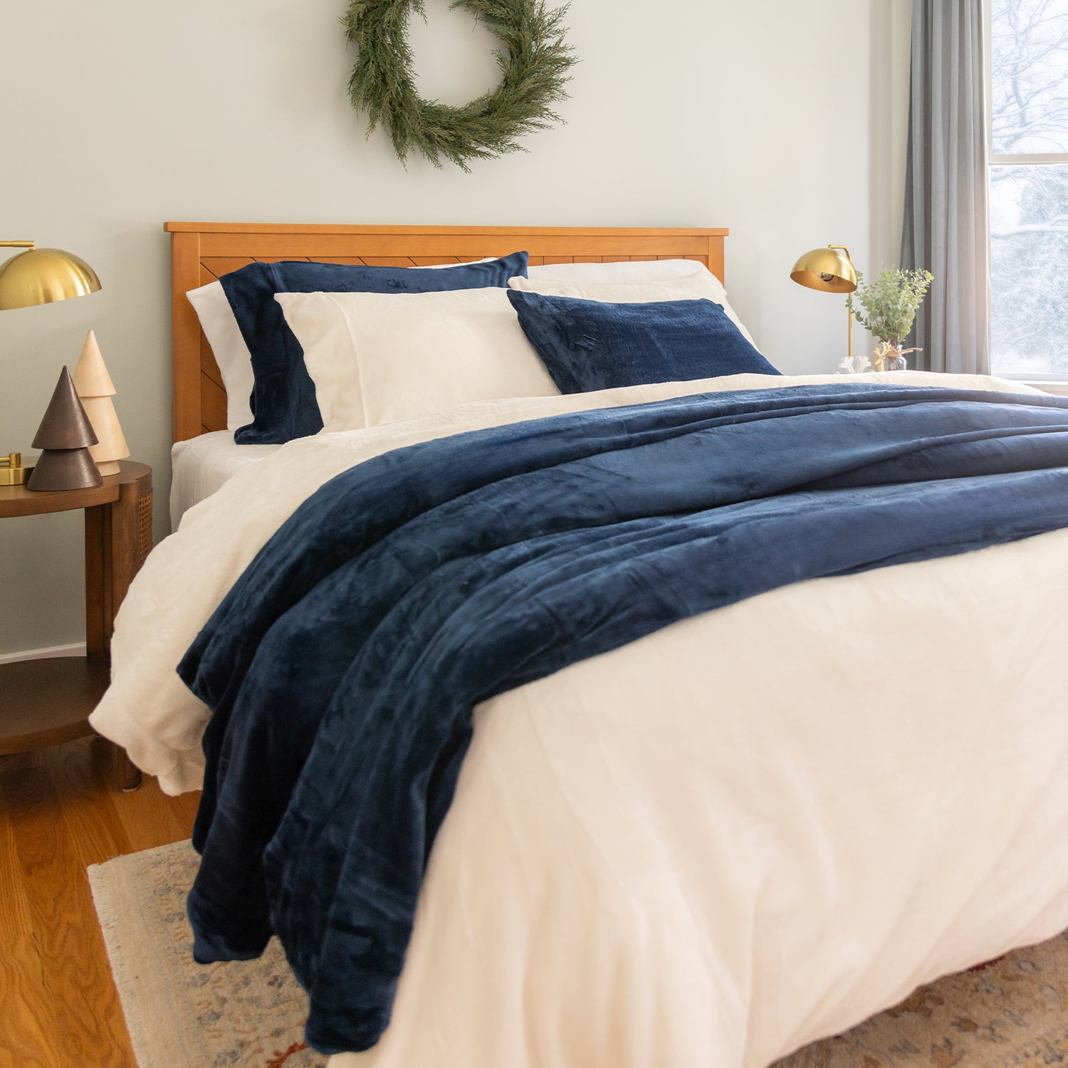 Bedroom with a bed covered in blue and white bedding, wooden headboard, and decorative items.