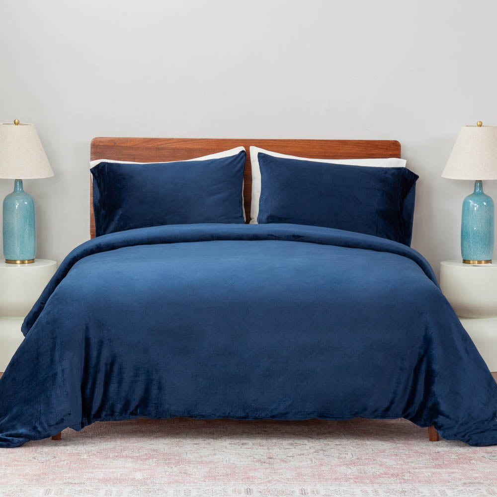 A bed made with the Dress Blue  VelvetLoft® Plush Duvet Cover Set and shams, creating a cozy and inviting look. 