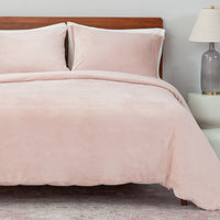 Bed with pink bedding and wooden headboard in a room setting.