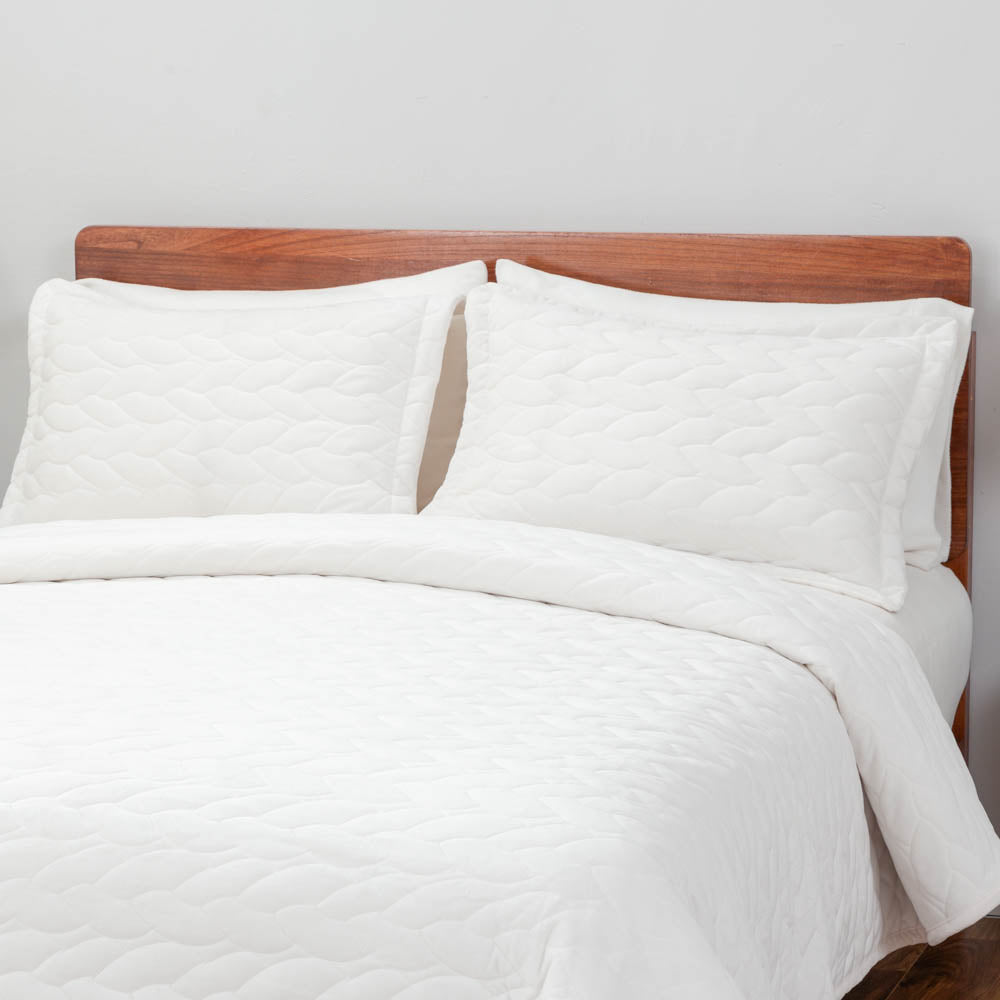 VelvetLoft® Quilt Set in White on a bed, close view of the quilt and pillow shams