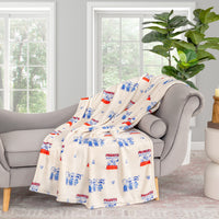Printed Peanuts 75th Anniversary throw draped neatly over a grey sofa in a living space.
