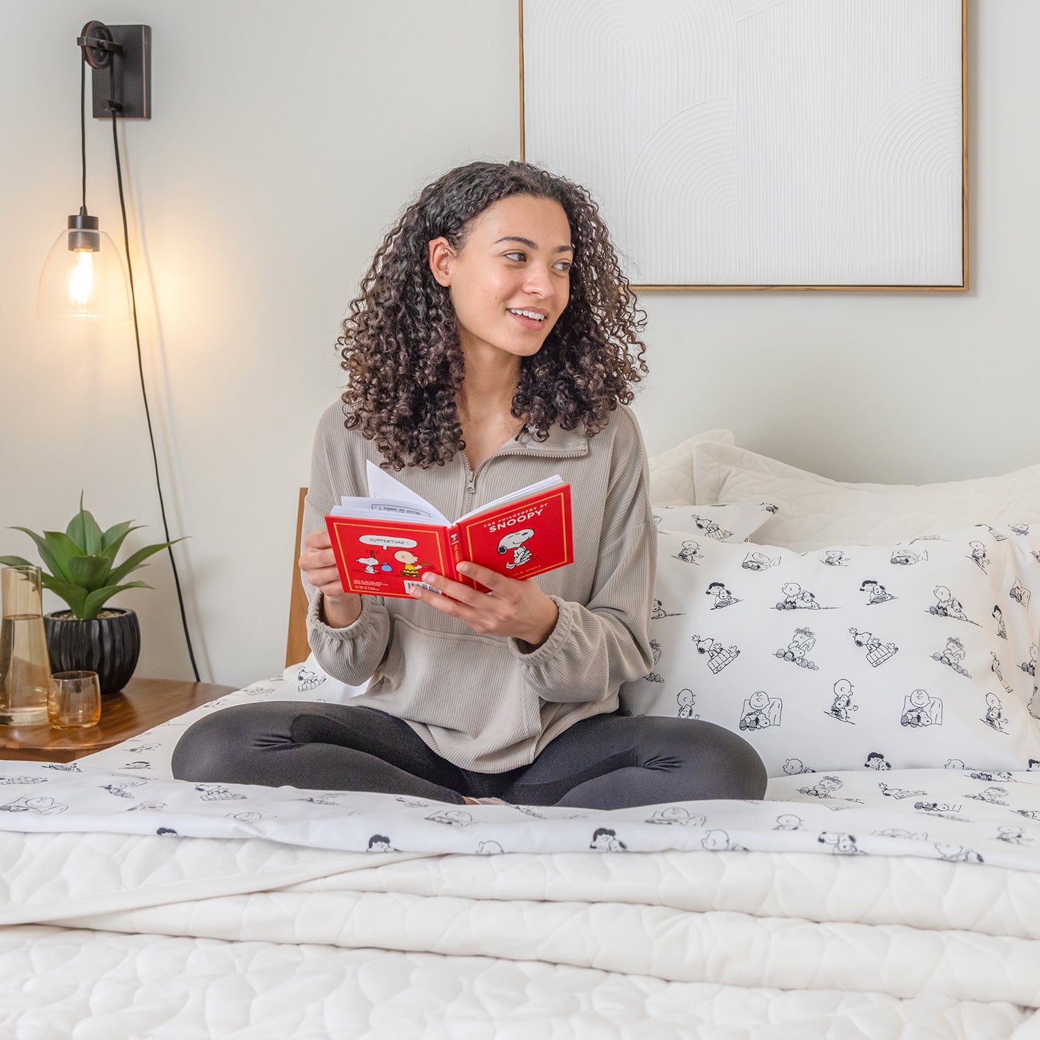 Woman reading a book on a bed in a cozy bedroom