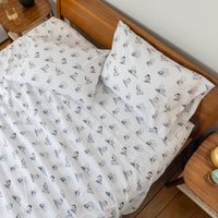 Bed with white bedding featuring black patterns on a wooden bed frame.