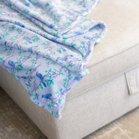 Close up of a cherry blossom printed throw laid on a beige sofa.