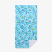 A blue peanuts beach towel laid flat on a white surface.