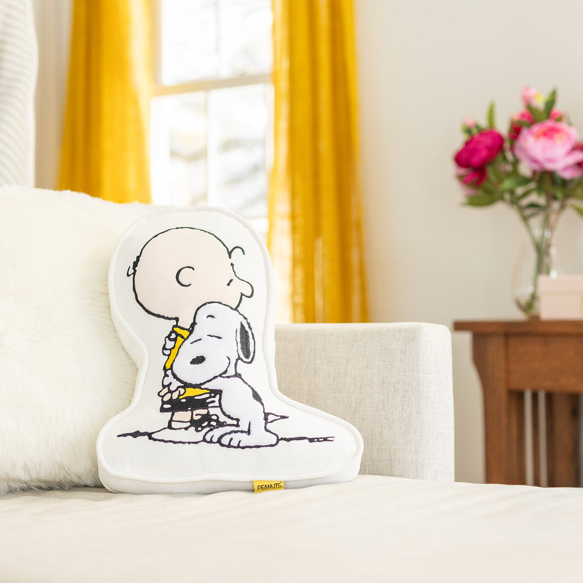 Charlie Brown & Snoopy embroidered pillow sitting on a beige sofa.