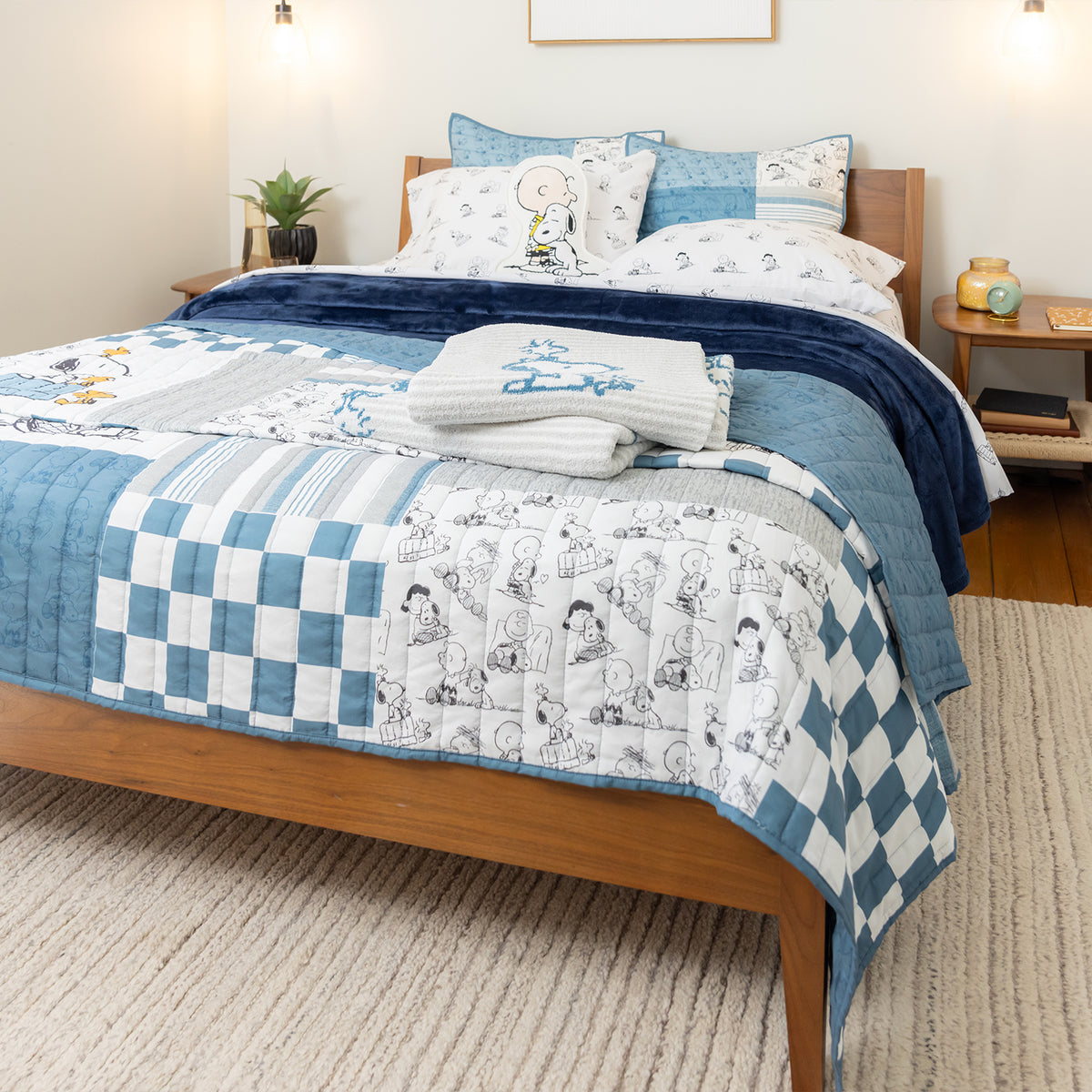 Bed with blue and white checkered quilt and cartoon-themed pillows in a bedroom setting.