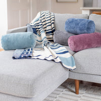 Gray sofa with colorful cylindrical pillows and a striped blanket in a living room setting.