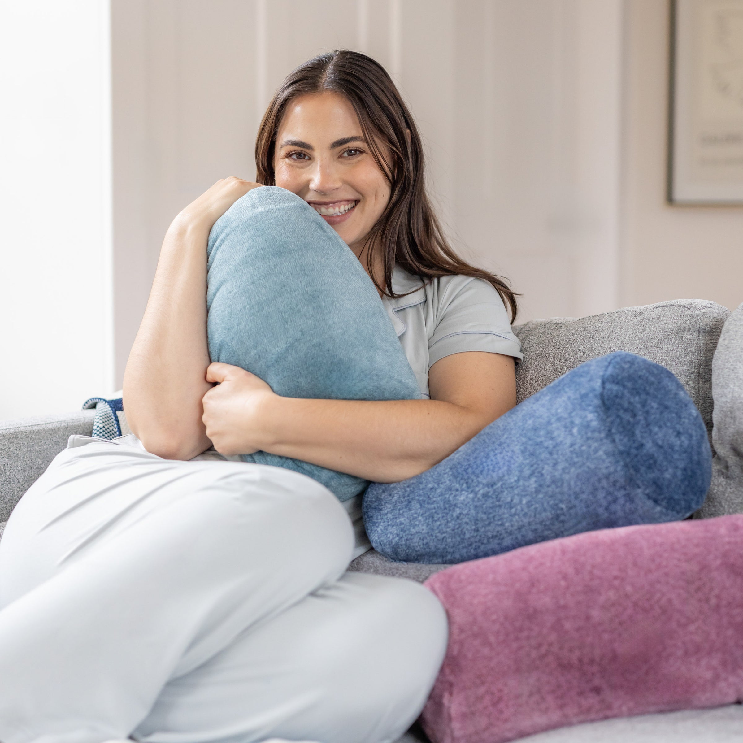 Woman sitting on a couch holding a large blue pillow