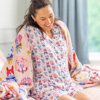 Woman wearing a colorful patterned outfit sitting on a couch.