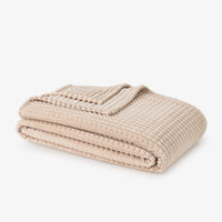 Folded beige blanket on a white background
